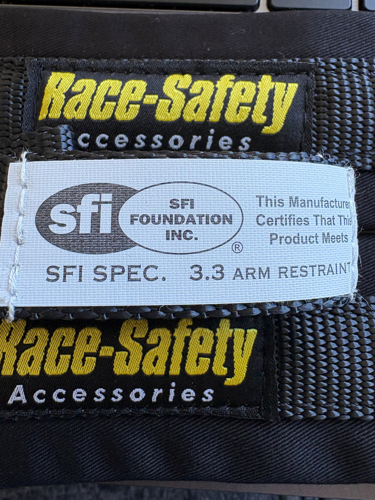 Race-Safety Accessories arm restraint label showing SFI Spec 3.3 identification on black webbing