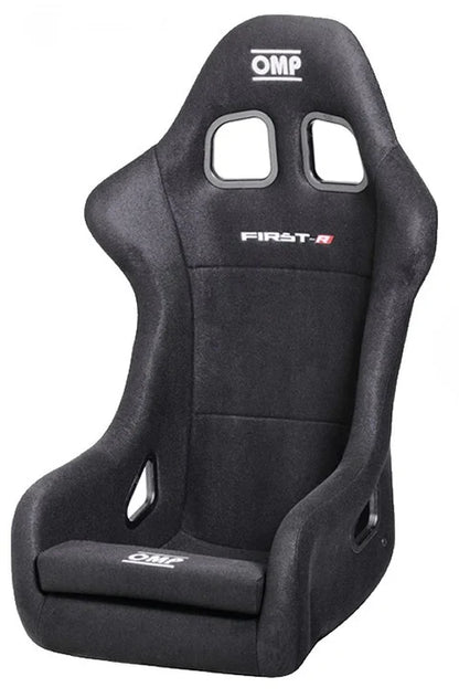 A black OMP First R racing seat with a fiberglass shell and velour upholstery, featuring side windows and harness slots.